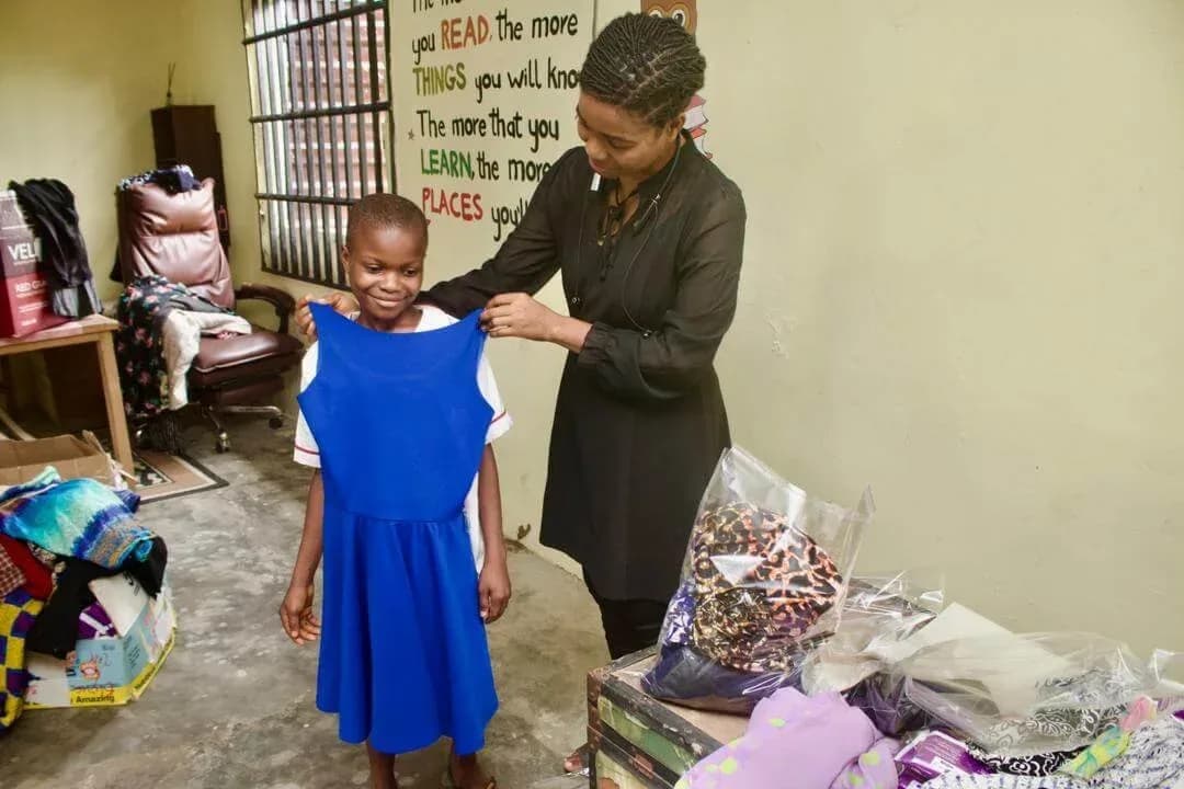 A child being fitted for a dress by GAMAID Garments