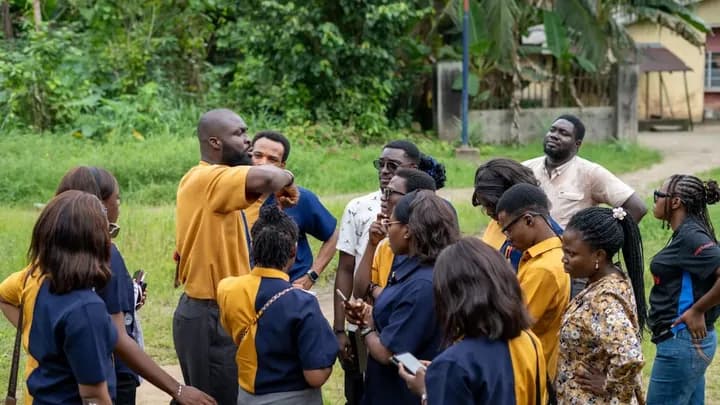 A GAMAID team leader briefs volunteers gathered outdoors before an outreach